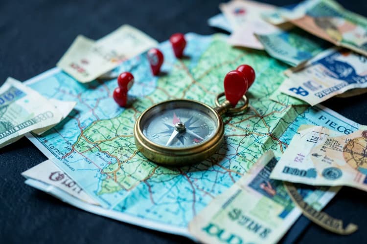 Um mapa com pinos de localização e uma bússola sobre notas de dinheiro, indicando análise de demanda local e investimento.